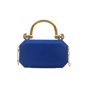 Blue acrylic box clutch evening bag detail with gold metal handle and chain strap for women.