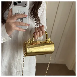 Dettaglio della elegante borsa da sera cilindrica dorata con finitura metallica e catena.