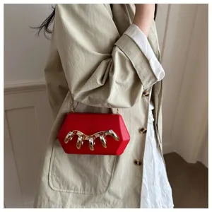 Detailansicht der roten Acryl-Clutch mit einzigartigem goldenen Nageldesign und Kette.