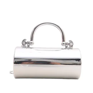 Dettaglio borsa da sera cilindrica in metallo argentato, pochette rigida lucida con manico.