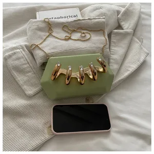 Nahaufnahme der gruenen sechseckigen Clutch mit Strass Metall Klaue und Kette Detail.