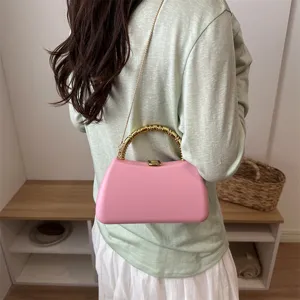 Pink PU hard shell box clutch handbag with gold bamboo handle worn on shoulder.