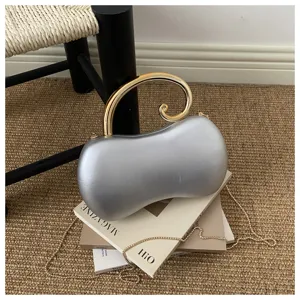 Vista dettagliata della borsa pochette argento metallizzato a arachide con manico oro e catena.