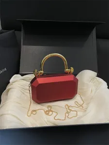 Red acrylic hard shell evening clutch bag with luxury gold handle and chain strap.