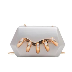 Detailansicht der silbernen Acryl-Abendtasche mit Goldkette und schickem Metall-Kristall-Dekor.
