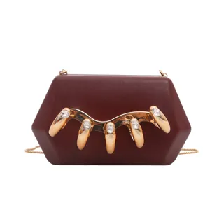 Detailansicht der dunkelroten Acryl-Hardcase-Clutch mit goldenen Krallen und Strasssteinen.