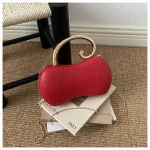 Vista dettagliata della pochette da sera rossa a forma di arachide con elegante manico dorato.