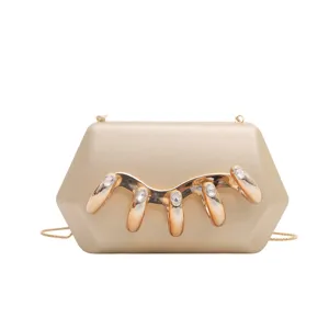 Detailaufnahme der goldenen Acryl-Clutch mit luxuriöser Kristall-Metallkrallen-Verzierung.