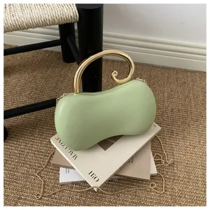 Vista dettagliata della borsa da sera a forma di arachide verde con manico dorato e catena