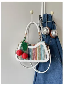 Sac à main en paille tissée d'été avec charmant pendentif cerise pour vacances plage.