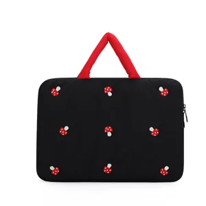 Detailansicht der stilvollen schwarzen gesteppten Laptoptasche mit süßen gestickten Pilzen.