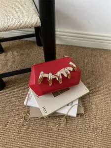 Stilvolle rote Acryl-Clutch Tasche mit goldener Metallkrallen-Dekoration und Kette.