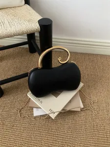Elegante borsa da sera nera a forma di arachide con manico dorato e catena raffinata.
