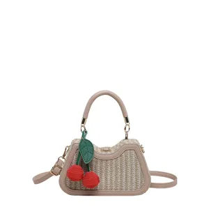 Sac à bandoulière en paille tissée avec charm cerise pour les vacances d'été à la plage.