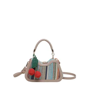 Vue détaillée du sac à bandoulière en paille tissée d'été avec un charmant pendentif cerise.