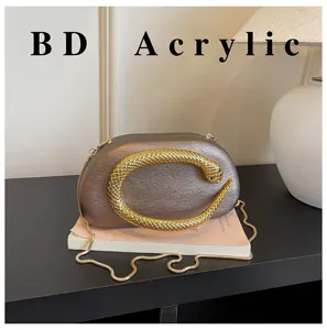 Κομψή γυναικεία μεταλλική οβάλ τσάντα clutch με εντυπωσιακή χρυσή λαβή φιδιού και αλυσίδα.