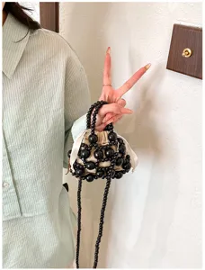 Mini bolso artesanal de cuentas negras con cordón de cinta blanca, ideal para el verano.