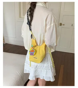 Borsa a tracolla in rete gialla elegante con cinturino chic e grazioso ciondolo per uso quotidiano.