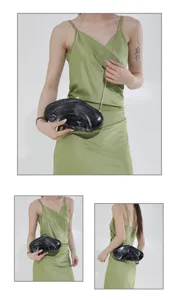 Detailed view of women's black marble acrylic hard shell evening clutch bag with gold chain.