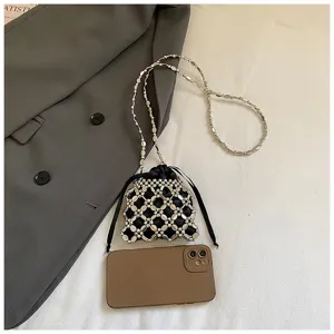 Handgemaakte kralen crossbody tas detail, stijlvolle metalen ketting en zwarte zak.