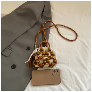 Mini bolso de mano artesanal de cuentas de madera con bolsa de cordón blanca y correa larga.