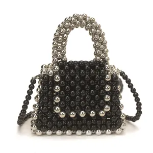 Close-up of handmade black and silver beaded mini handbag with top handle and strap.