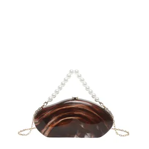Acrylic clutch bag detail showing the unique brown marble pattern and elegant faux pearl handle.