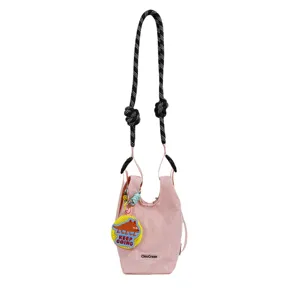 Dettaglio borsa a tracolla in rete rosa, con cinturino nero bianco e simpatico ciondolo dinosauro.