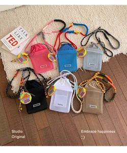 Vista detallada de bolsos cruzados de malla colorida con correas trenzadas y dijes muy bonitos.