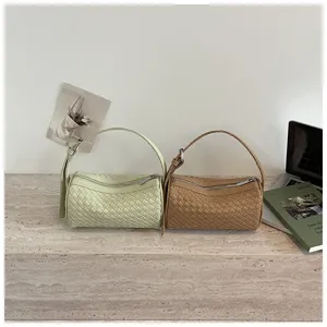 Woven cylindrical handbag detail shot, minimalist style PU leather top handle bag.