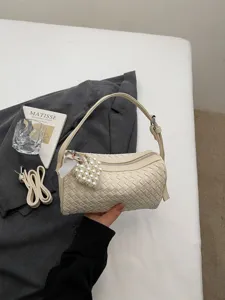 Woven cylindrical handbag for women, stylish shoulder bag with pearl heart pendant and strap.