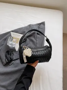 Black woven cylindrical shoulder bag for women, stylish leather handbag with pearl charm.