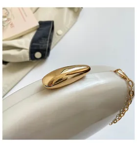 Primo piano dettaglio della borsa pochette in acrilico bianco con chiusura e catena dorate.