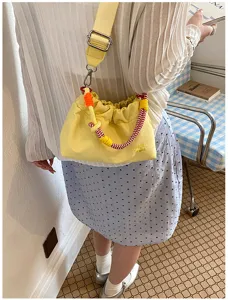 Sac bandoulière tissé de couleur bonbon avec sangle large et détails de poignée tressée.