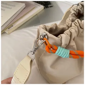 Vue détaillée de la quincaillerie du sac seau, fermoir et poignée en corde tissée orange.