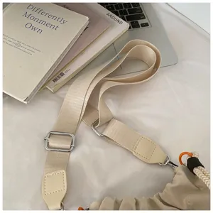 Gros plan sur la bandoulière de sac en toile beige avec boucle en métal et languette en PU.