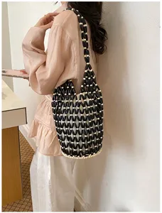 Detail view of black and white acrylic beaded bucket bag showing hollow woven structure.