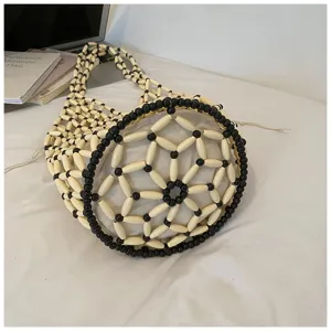 Close-up of black and white beaded bucket bag with hollow mesh design and inner drawstring pouch.