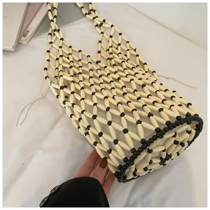 Detailed shot of hollow woven beaded shoulder bucket bag, black and white mesh design.