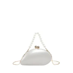 Detailaufnahme einer eleganten, weißen Abendtasche in Mangoform mit stilvollem Perlenhenkel.