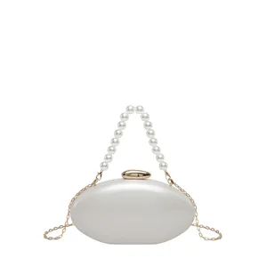 Elegant white acrylic oval clutch bag with pearl handle and gold chain for women evening party.