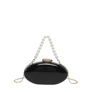 Black acrylic oval clutch bag with pearl handle and gold chain strap for women evening party.