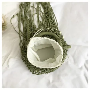 Green woven fringe bucket bag detail, handmade macrame texture with white drawstring inner lining.