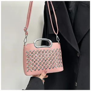Détail de sac à main rose avec des strass brillants et poignée en métal élégante.