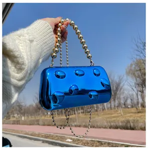Dettaglio della borsa da sera in acrilico blu metallizzato lucido con tracolla a catena di perle.