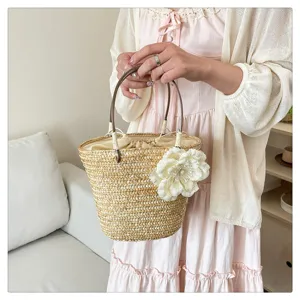 Straw woven handbag detail view featuring elegant fabric flower decoration for summer.