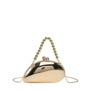 Nahaufnahmendetail der goldenen metallischen mangoförmigen Clutch mit Perlenhenkelkette.