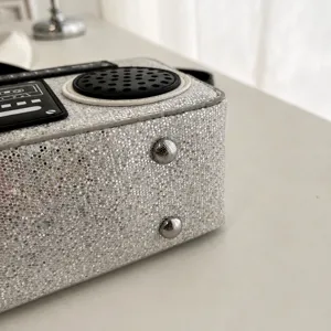 Detailansicht der silbernen Glitzer Boombox Umhängetasche mit stabilen Metallbodenknöpfen.