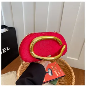 Stylish red evening bag with unique gold metal handle and chain strap for women.