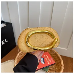 Detail view of the gold textured evening clutch with a statement metal ring handle and chain.